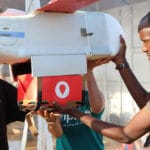 Technik z Zipline instaluje kartonowe pudło z papierowym spadochronem w drone w Muhanga, 50 km na zachód od Kigali