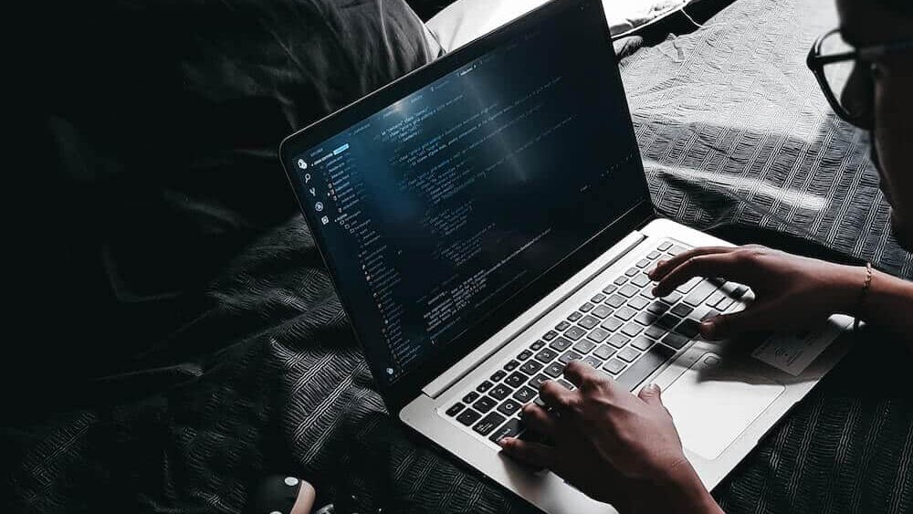 Programista tworzy kod na łóżku