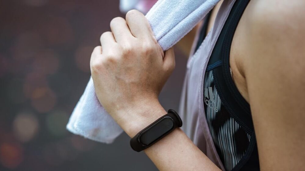 Jaka opaska sportowa? Kobieta ze smartbandem trzymająca ręcznik