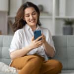 Kobieta na sofie korzystająca ze smartfona